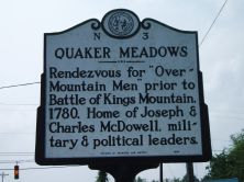 A metal sign enumerating details of the Quaker Meadows historic site.