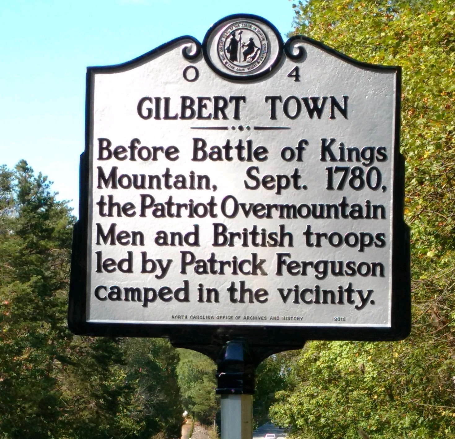 Metal sign discussing Gilbert Town. Gray metal with black text. 